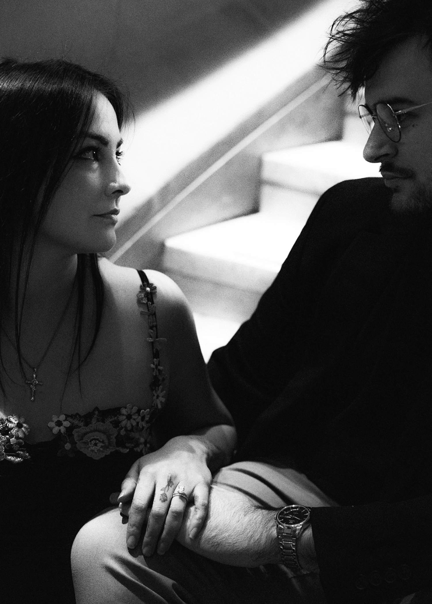 A close portrait of Amanda and Ethan seated on stone steps, her hand resting in his.